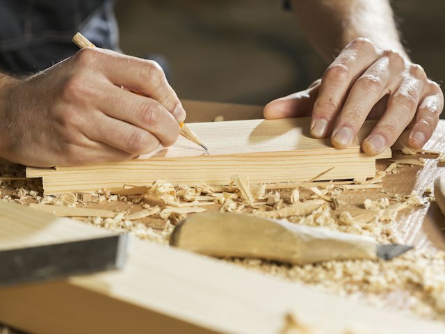Un artisan trace une pièce de bois dans son atelier